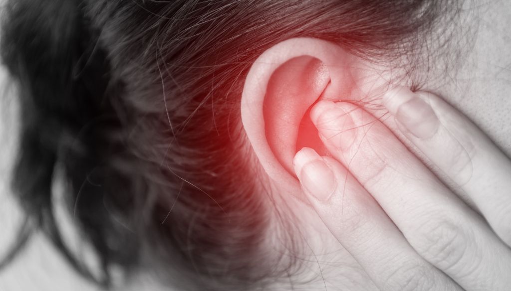 Close up of a person with a earache, holding their ear,